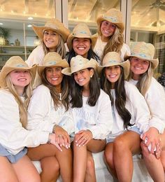 a group of women sitting next to each other wearing hats