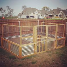 an outdoor chicken coop in the middle of a yard with houses in the back ground