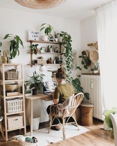 a person sitting at a desk with plants on the wall and shelves above them,