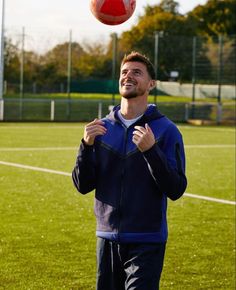 a man standing on top of a field with a soccer ball in the air above his head