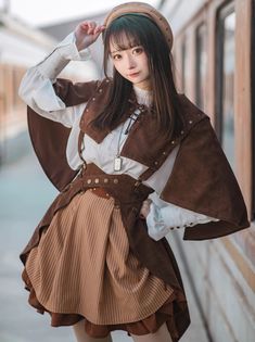 a woman wearing a brown and white outfit standing next to a train station wall with her hands on her head