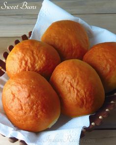 four oranges sitting in a basket on top of a wooden table next to a white towel