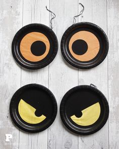 four black paper plates with yellow eyes on them