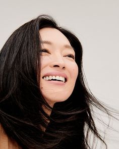 a woman with long black hair smiling and holding her head up to the side,