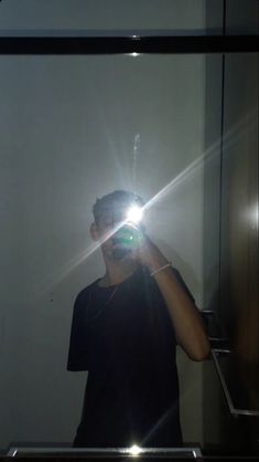 a man taking a selfie in front of a mirror with the light shining on him