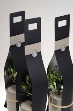 three black and white vases with plants in them sitting on top of each other