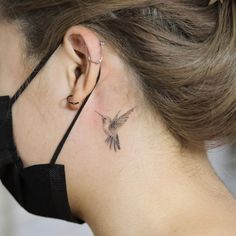 a woman with a small bird tattoo on her left side behind the ear and behind the neck