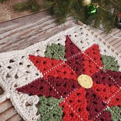 a crocheted christmas ornament on a table next to a fir tree