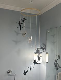 a bathroom with birds hanging from the ceiling next to a mirror and towel rack in front of it