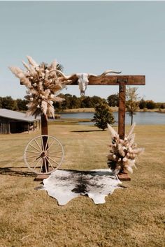 an outdoor ceremony setup with flowers, feathers and a wagon on the grass in front of a lake