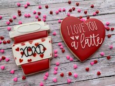 two decorated cookies sitting next to each other on top of a wooden table with pink and red sprinkles