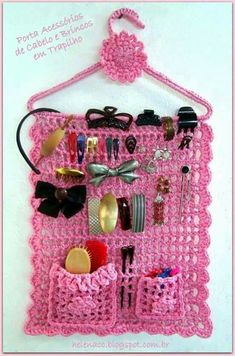 a pink crocheted wall hanging with lots of items on it