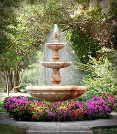 a water fountain surrounded by flowers and trees