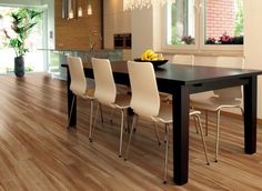 a dining room table with white chairs next to an open floor plan and large windows