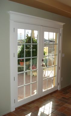 the inside of a house with double doors and brick flooring in front of it