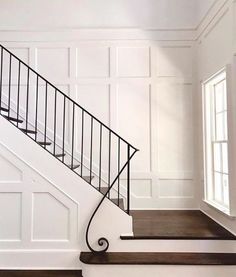 a white staircase with black railing and wood flooring