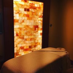 a spa room with a stone wall in the background and a massage table on one side