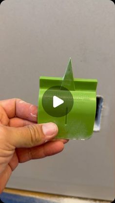 a person holding a green object with a video playing button on the screen in front of them