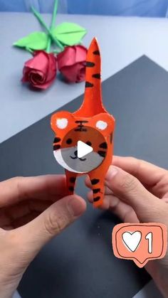 someone is holding up a paper cut out of a tiger face with flowers in the background