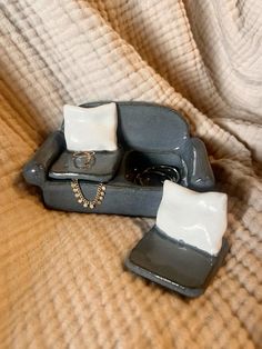 two pieces of ceramic sitting on top of a bed next to each other with rings in them