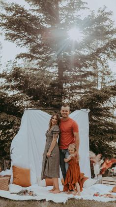 a man and woman standing in front of a tent with two small children on it