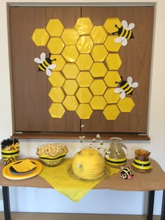 a table topped with cakes and desserts next to a honeycomb wall hanging on the wall