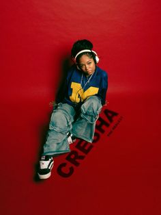 a young boy sitting on top of a red wall with headphones in his ears