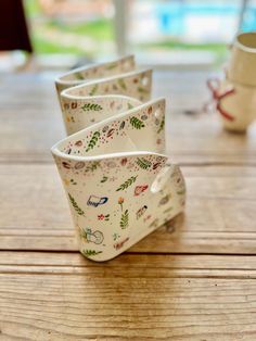 three cups sitting on top of a wooden table next to each other, with designs on them