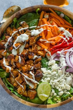 a salad with chicken, carrots, lettuce, onions and other vegetables