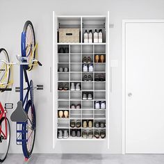 two bikes parked next to each other in front of a white wall with shelves on it