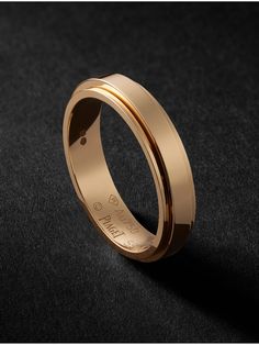 a gold wedding ring on a black surface