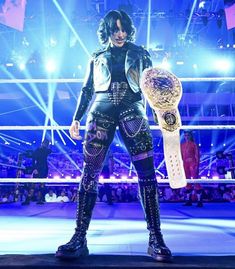 an image of a woman holding a trophy in front of a crowd at a wrestling match