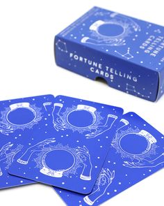 four blue fortune telling cards sitting on top of a white table next to a box