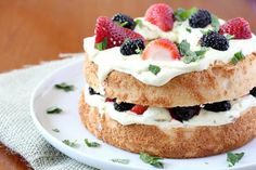 the cake is topped with fresh berries and whipped cream on it's top, sitting on a white plate