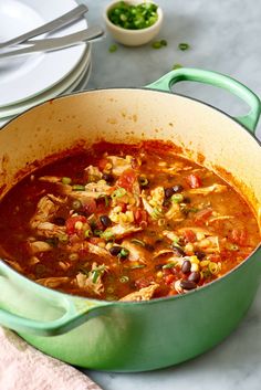 a green pot filled with chicken and beans