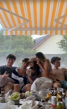 a group of people sitting on top of a couch next to each other under a tent