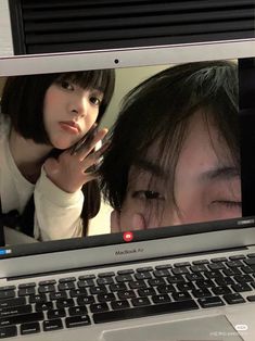 a laptop computer sitting on top of a desk with an image of two women in the screen