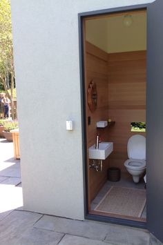 an open door to a bathroom with a toilet and sink on the outside patio area