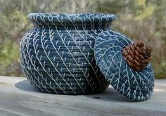 a large blue vase sitting on top of a wooden table next to a pine cone