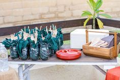 the table is set up with green bags and utensils for guests to eat