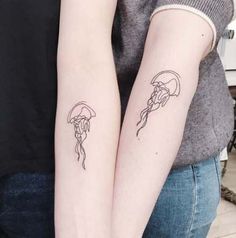 two people with tattoos on their arms holding each other's hands and one has a jellyfish tattoo on its arm