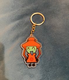 an orange and green keychain with a cartoon character on it