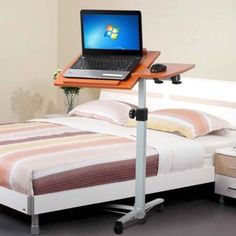 a laptop computer sitting on top of a bed next to a desk with a mouse