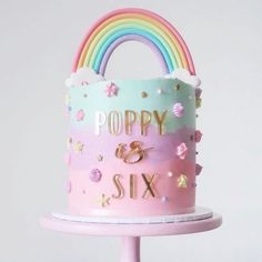 there is a pink cake with rainbows and stars on the top that says poppy six