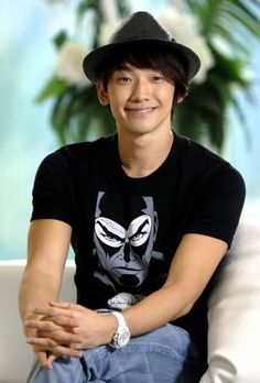 a man sitting on top of a white couch wearing a black hat and t - shirt