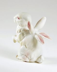 a white ceramic rabbit figurine sitting on its hind legs