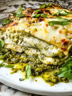 a white plate topped with lasagna covered in pesto