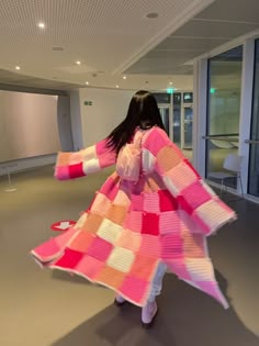 a woman is standing in an empty room with a pink and white blanket on her back