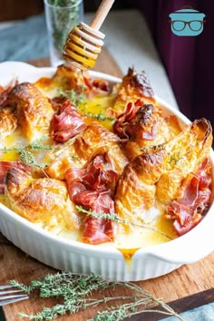 a casserole dish with ham and cheese in it being drizzled with honey