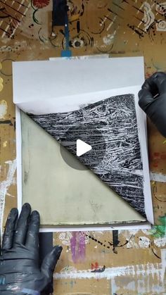 someone is making an art project with black and white paper, gloves and paint on the wall